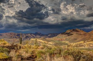 Panoramic view of storm-clouds over mountains in the try desert with cacti and vegetation